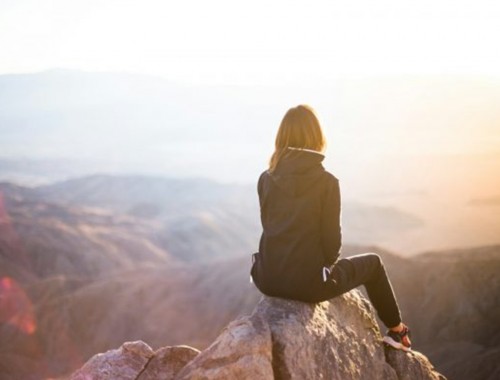 A girl setting on the top of a mountain 